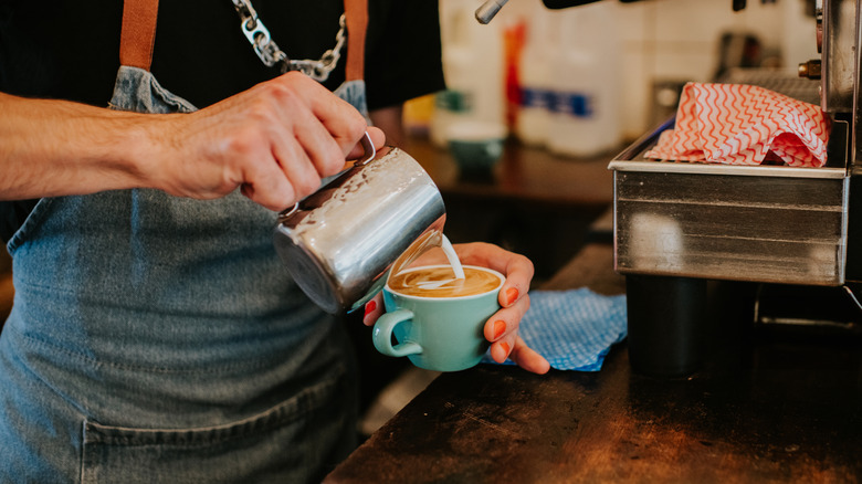 A barista pouring a cup of coffee.