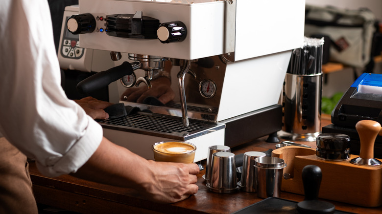 A barista prepares coffee using an espresso machine