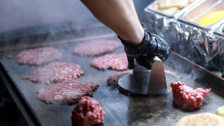 Person using burger press to press down burger patty.