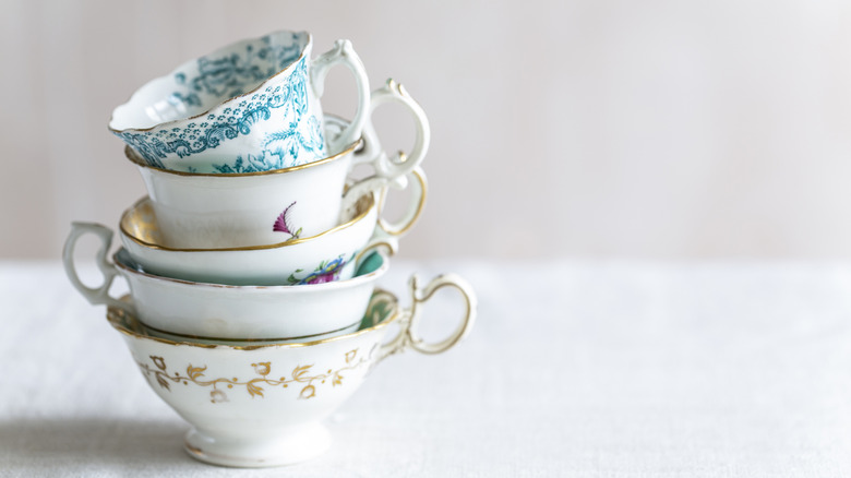 A stack of vintage tea cups sits on a table
