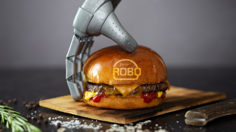 RoboBurger-branded burger held by a robot hand