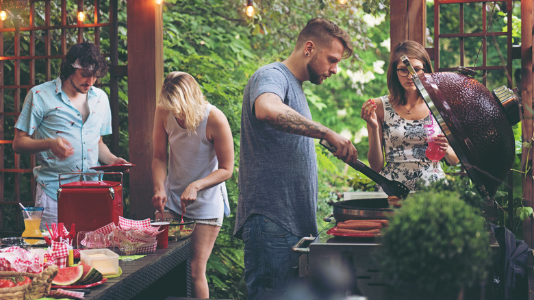 Man cooking outdoors for a party of people