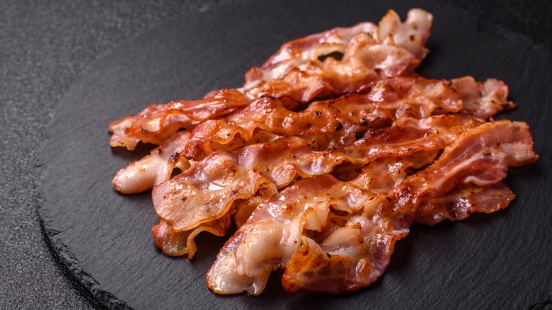 Crispy bacon slices on a black plate
