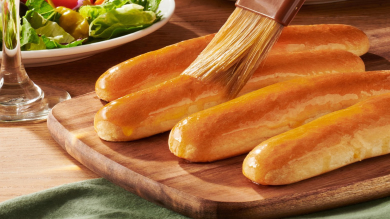 Someone brushes Olive Garden breadsticks with butter or oil