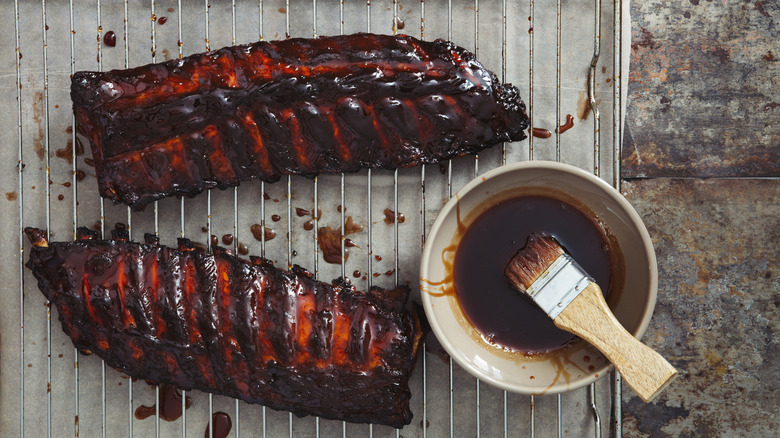 a rack of ribs next to bbq sauce