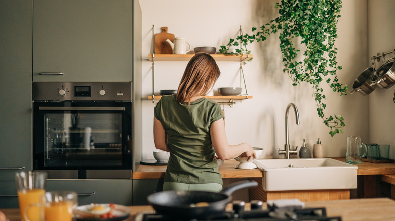 A homeowner in a modern kitchen with a plaster backsplash.