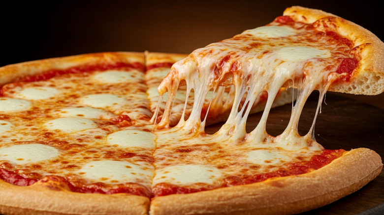 Closeup of a cheese pizza slice being lifted from the rest of the pie