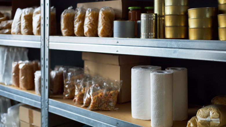 Cans, dried pasta, and paper towels on shelves.