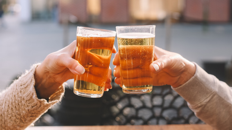 Two people clinking glasses of beer