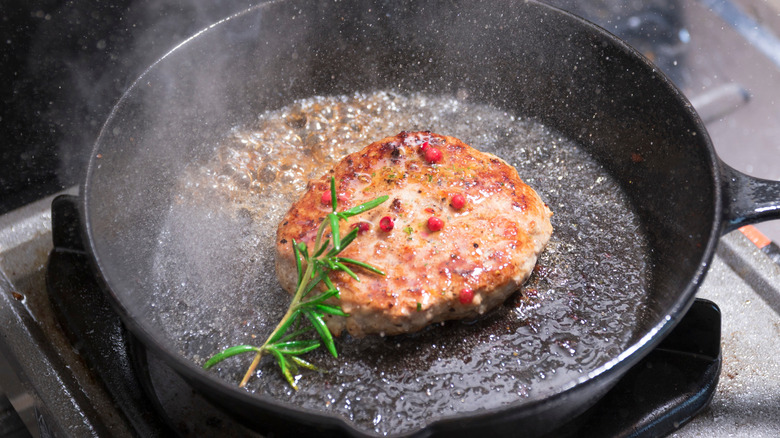 Hamburger steak cooking in cast iron pan