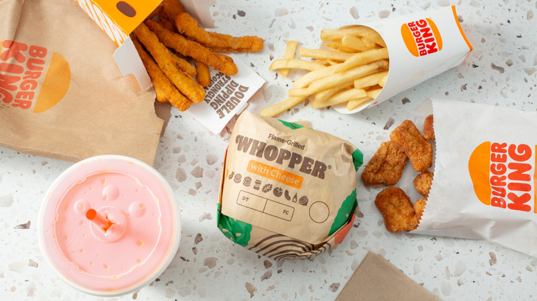 An array of food from Burger King, including a Whopper, nuggets, fries, a drink, and chicken fries