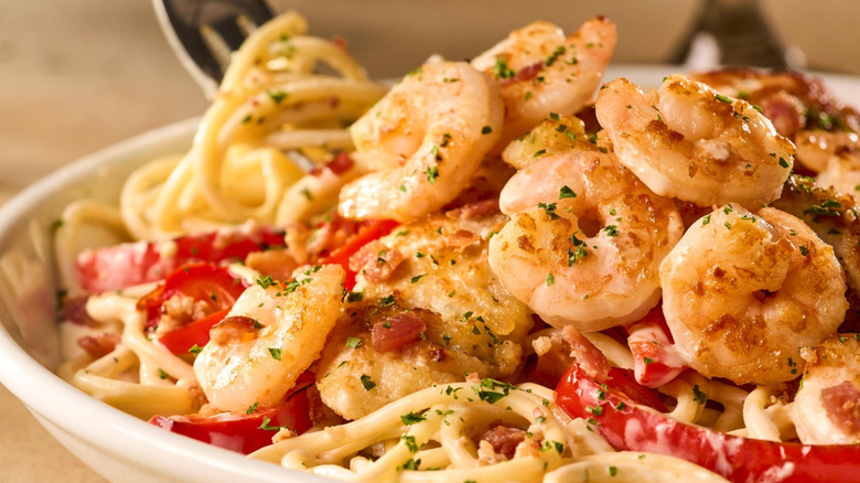A bowl of Olive Garden Carbonara with chicken and shrimp sits on a table