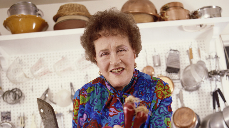 Julia Child holding vegetables in the kitchen of her home