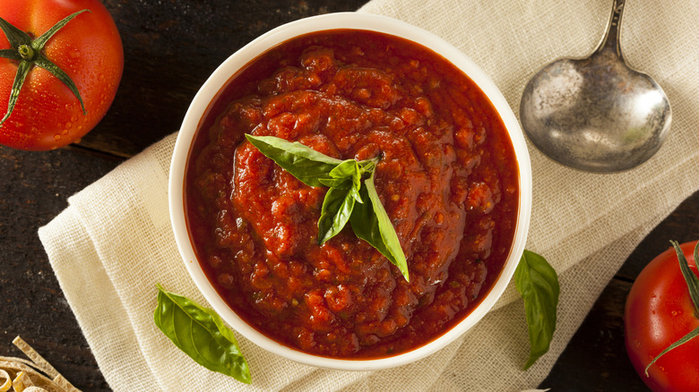 A bowl of marinara sauce topped with fresh basil