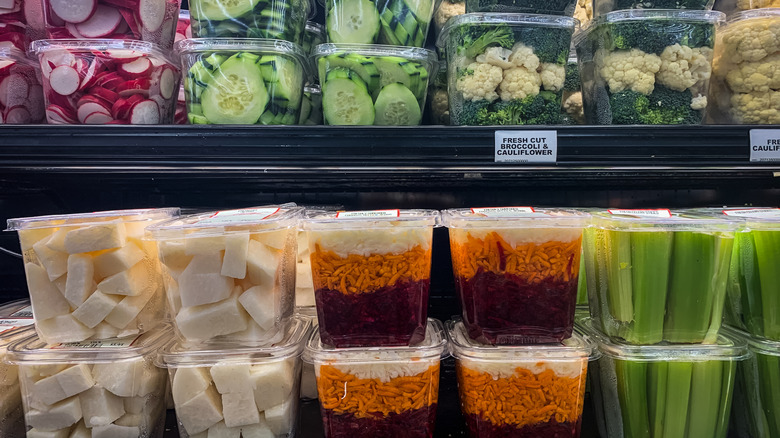 Various plastic containers of chopped vegetables on black shelves