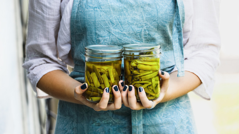 Young woman holding Mason jars with pickled beans