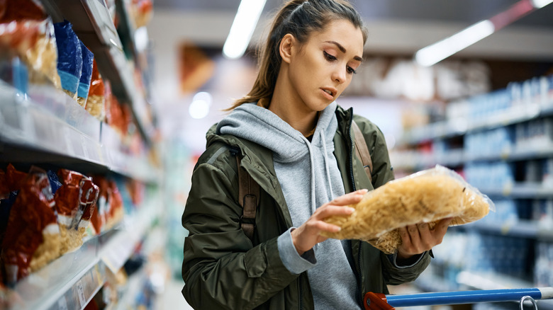 Woman looking at bag of pasta in a supermarket