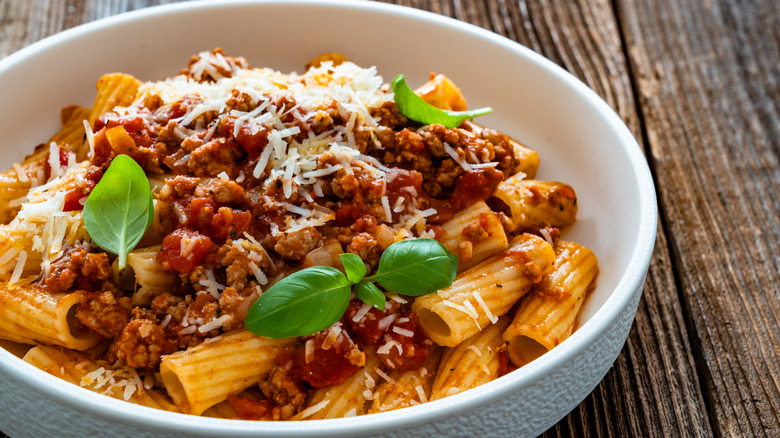 rigatoni with ragu in a white plate with fresh basil