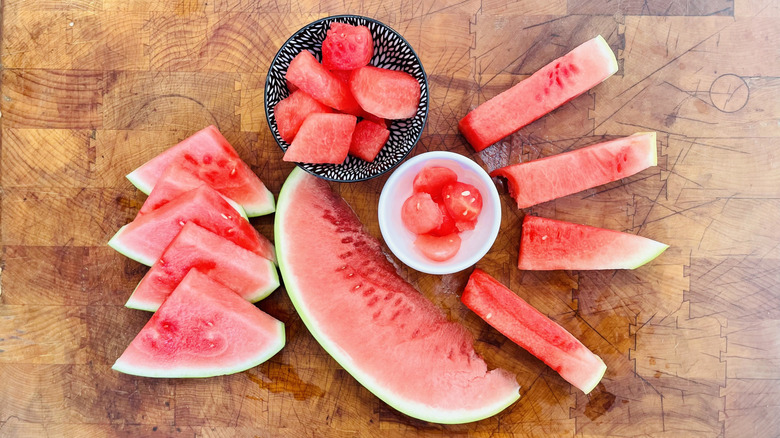 Sliced watermelon in various shapes on cutting board
