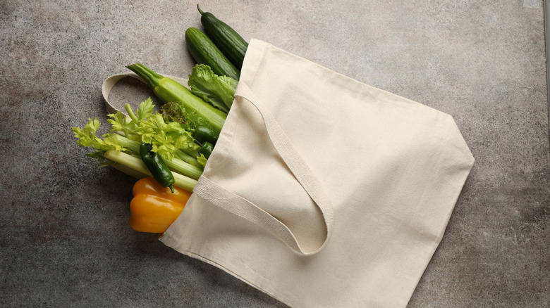 Canvas tote with groceries lies flat on gray surface