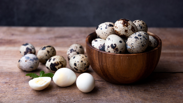 Wooden bowl of quail eggs by hard-boiled quail eggs