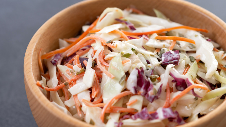 Macro shot of shredded cabbage, carrots, and purple cabbage from a bagged coleslaw mix in a wooden bowl