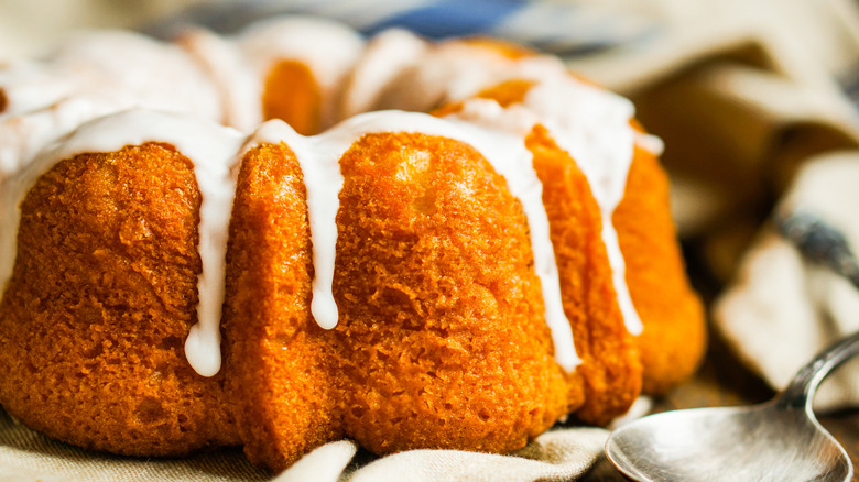 Closeup of a pumpkin-colored bundt cake with a cream cheese frosting drizzle