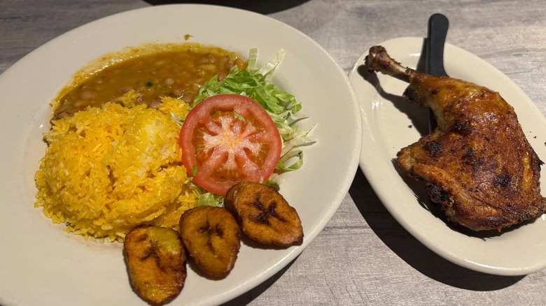 Chicken thigh and plate with rice, salad, and beans
