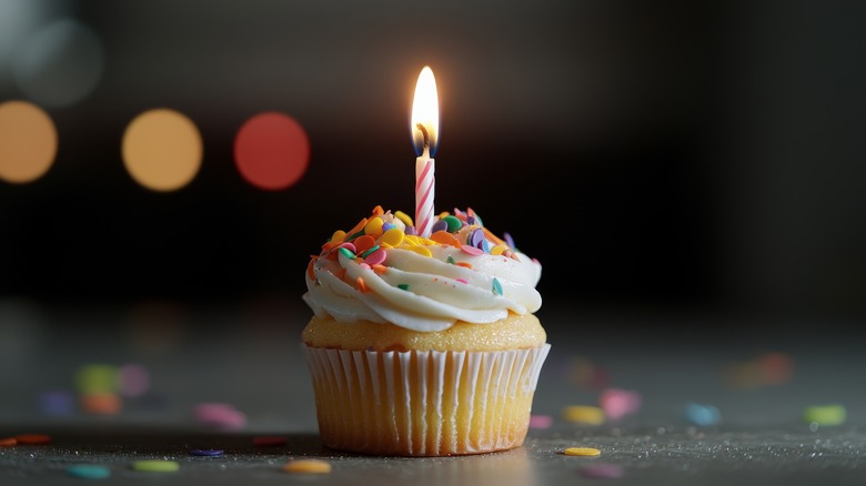 Cupcake with rainbow sprinkes and lit-up birthday candle