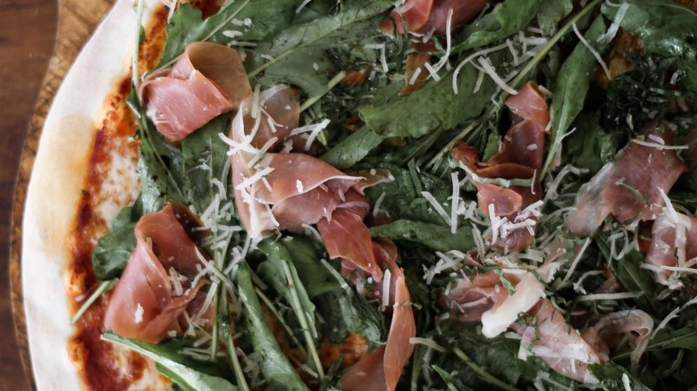 Close-up of La Rustica pizza with leafy greens and proscuitto