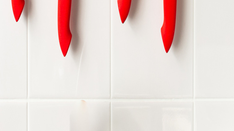 A magnetic knife strip with knives on the wall