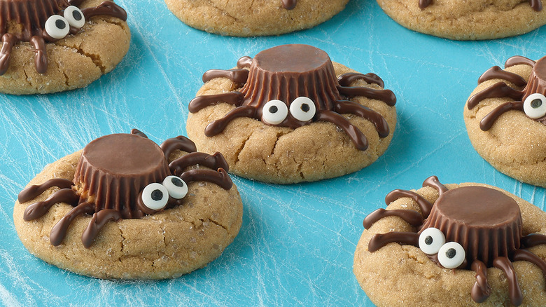 Peanut butter cookies with spider topping on blue surface