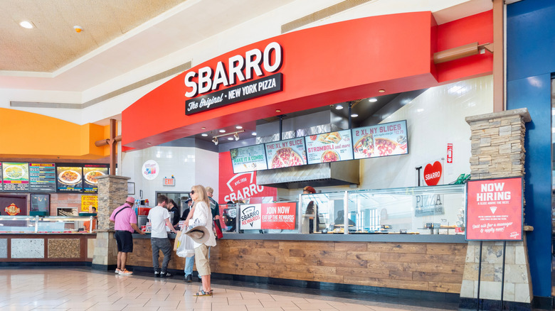 People stand near or at the counter of a mall Sbarro location