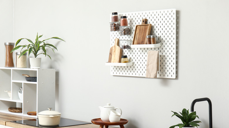Pegboard used for spices, cutting boards, and a dish towel in a neutral kitchen