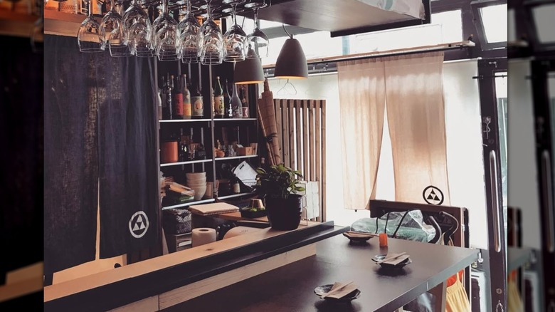 The interior of the restaurant, a counter with bottles behind it and glasses hanging above