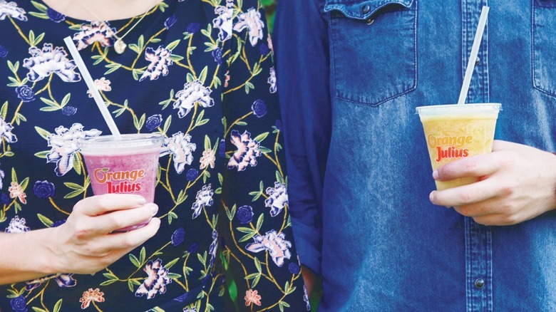 People holding Orange Julius drinks