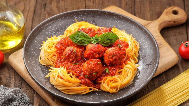 Homemade spaghetti and meatballs sit on a black plate