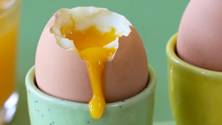 A jammy boiled egg is cracked in an egg cup.