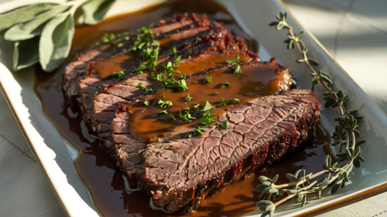 Sliced brisket covered in gravy and herbs
