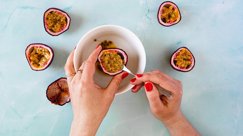 hands extracting passion fruit pulp