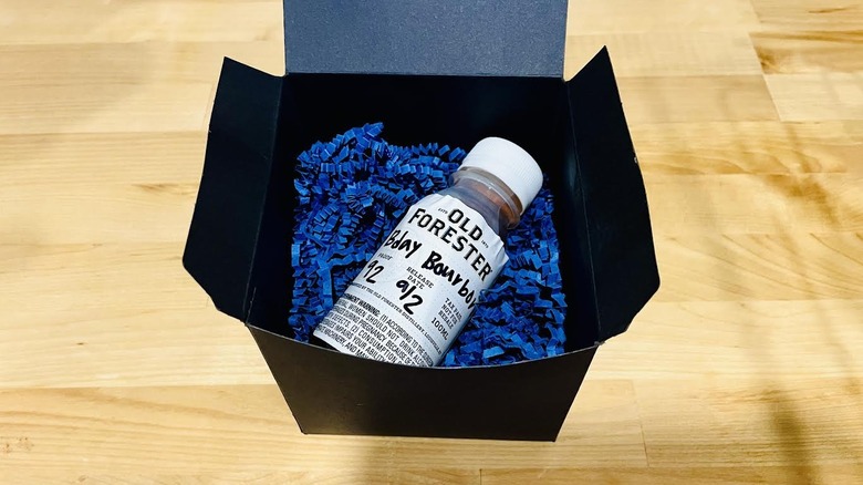 Sample bottle of Old Forester Birthday Bourbon 2025 in black gift box with blue paper shavings