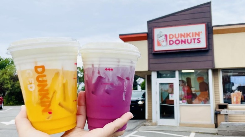 Hand holding new Daydream Refreshers in front of Dunkin' storefront