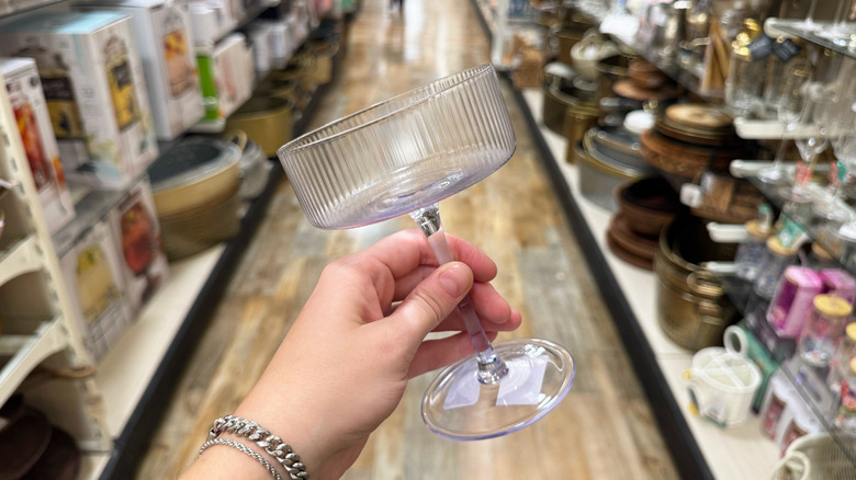 A hand holds up a lilac coupe glass