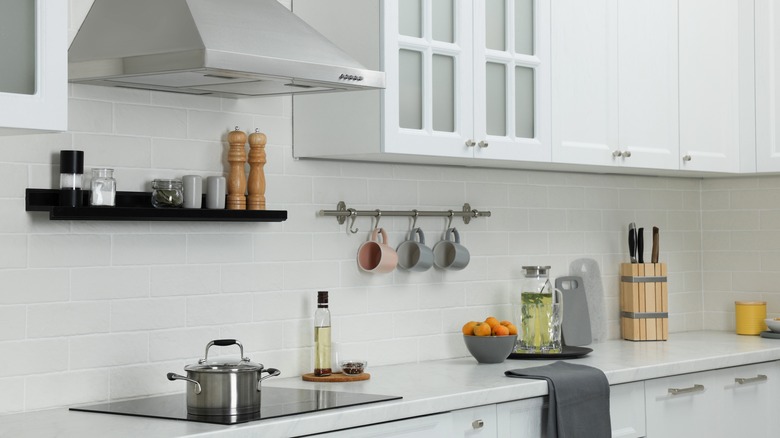 A white kitchen with black shelf installed over the stove