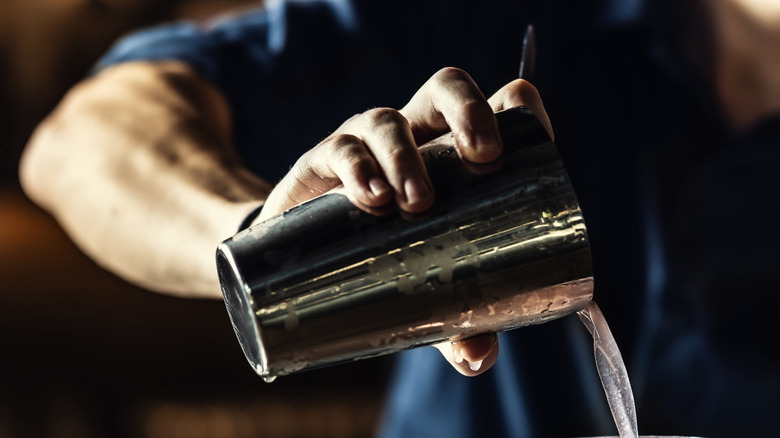 Someone uses a shaker to pour a cocktail
