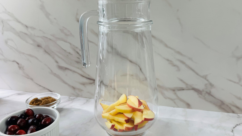 Sliced apples in a glass jug on a counter