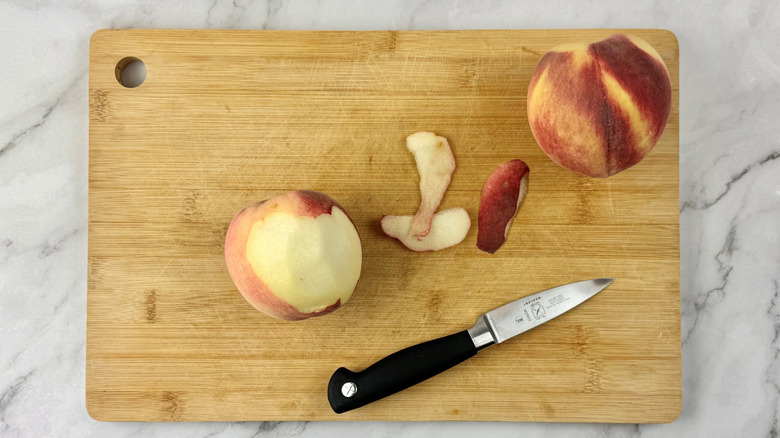partially peeled peaches with a knife