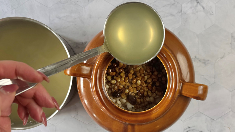 ladling bean water into dutch oven with beans