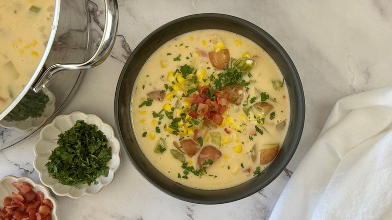 Bowl of corn chowder with bacon and parsley garnishes