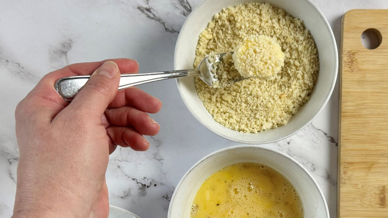 Fork holding goat cheese slice in breadcrumbs